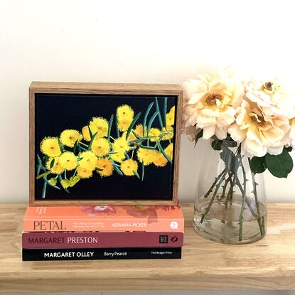 Explosions of bright yellow wattle on a dark blue background. Framed in natural wood.