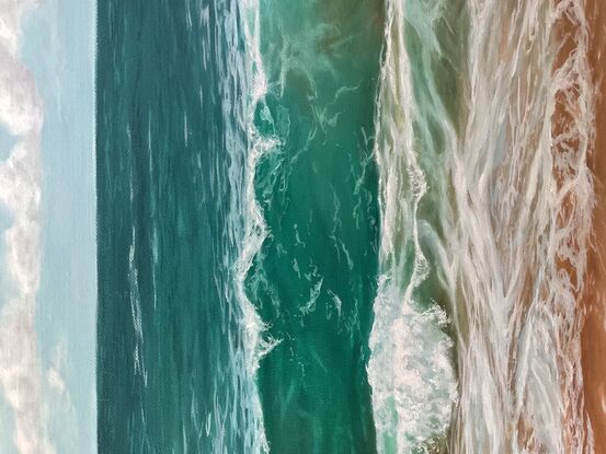 Turquoise waves breaking on a beach under an overcast sky. 