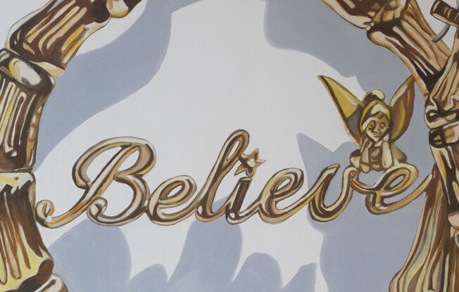 Close up of gold hoop earrings with the word 'believe'