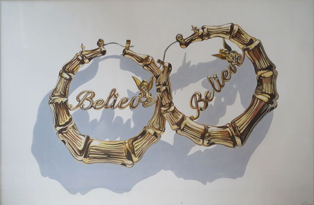 Close up of gold hoop earrings with the word 'believe'