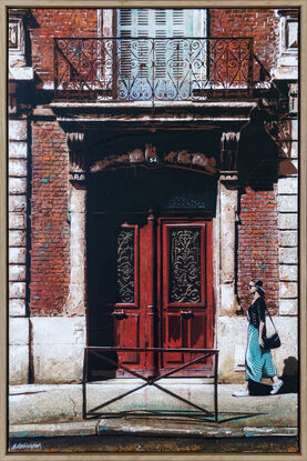 a woman walks past a set of old red doors in France