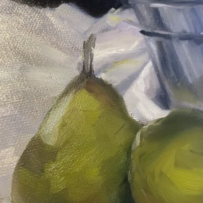 Two ripe green pears and some strawberries in a white bowl, with their reflections in a metal tin. On a white tablecloth.