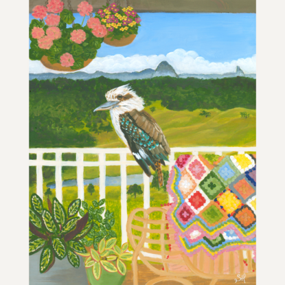 Kookaburra sitting on a verandah fence against a landscape backdrop inspired by the Sunshine Coast hinterland. Including plants and a cosy chair with colourful crochet blanket in the forecground.