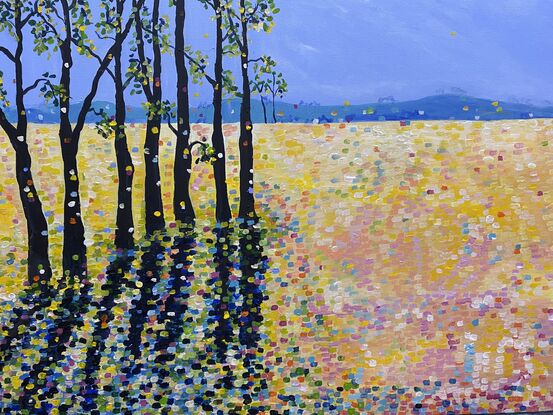 Bold striking brown black trees in two groups on the sides of the painting contrast with the sunny yellow fields   The striking  tree shadows create drama and interest against the medley of sunshine whilst  splashes of electric colour warm the scene. This is a striking piece to add vibrancy and interest to a room. There is an underlying feeling of positivity and happiness with the bright colour. 