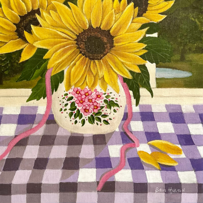 vase of 3 sunflowers on a purple gingham table cloth against a window view hinterland inspired landscape scene