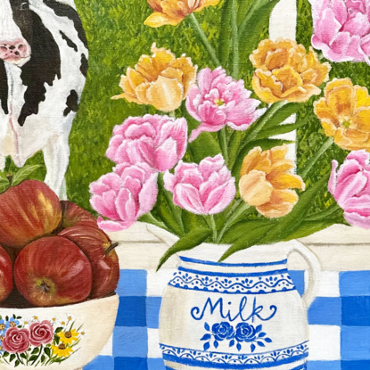 still life scene featuring a white and blue milk jug with filled with yellow and pink foxtrot tulips next to a bowl filled with red apples, against a hinterland inspired landscape window view backdrop and a blue gingham table cloth