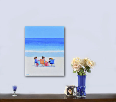 A colourful beach scene with three young women sitting in beach chairs chatting in front of the ocean.