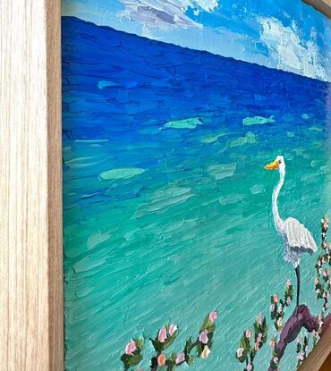 A textured white Egret standing on a log admiring the calm turquoise ocean.