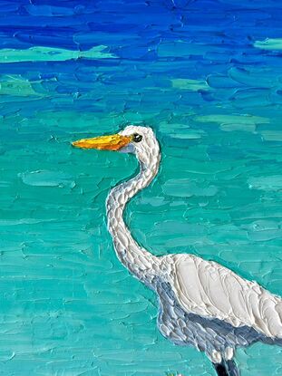 A textured white Egret standing on a log admiring the calm turquoise ocean.