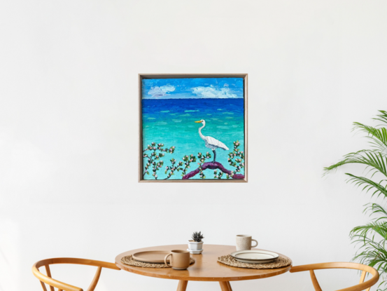 A textured white Egret standing on a log admiring the calm turquoise ocean.