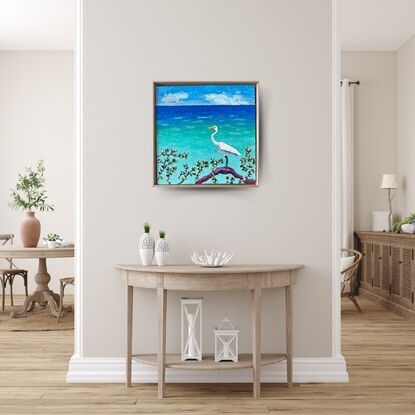 A textured white Egret standing on a log admiring the calm turquoise ocean.