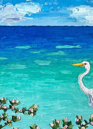 A textured white Egret standing on a log admiring the calm turquoise ocean.