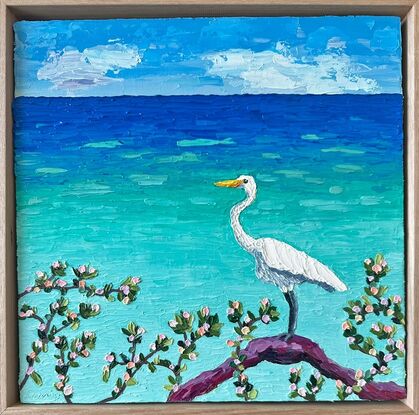 A textured white Egret standing on a log admiring the calm turquoise ocean.