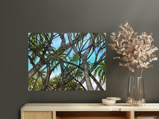 Pandanus palm trees silhouette against blue sky and the beach.
