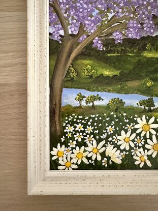 Jacaranda tree above a field of white daisies set against a a hinterland inspired backdrop with rolling green hills and blue sky