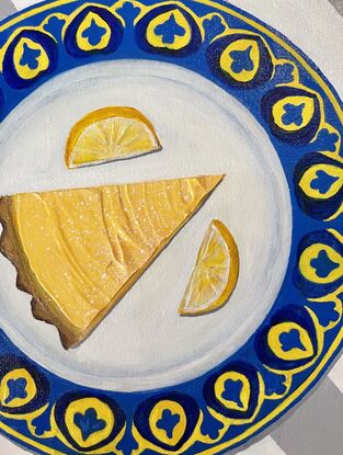 Slice of citrus tart on a blue and yellow plate on striped grey and white tablecloth 