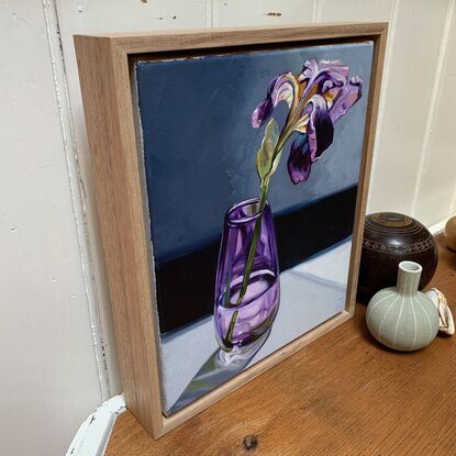 A single purple iris in a handblown purple glass vase