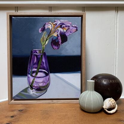 A single purple iris in a handblown purple glass vase