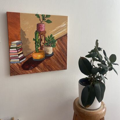 A stool, a stack of books, pot plants in a living room
As the afternoon light filters in 