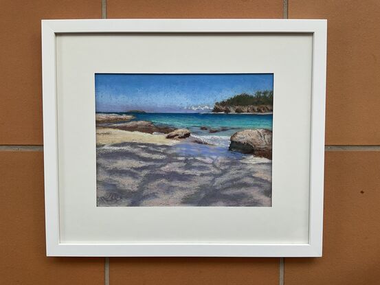 Tree shadows on sand with turquoise water and  headland in the background.