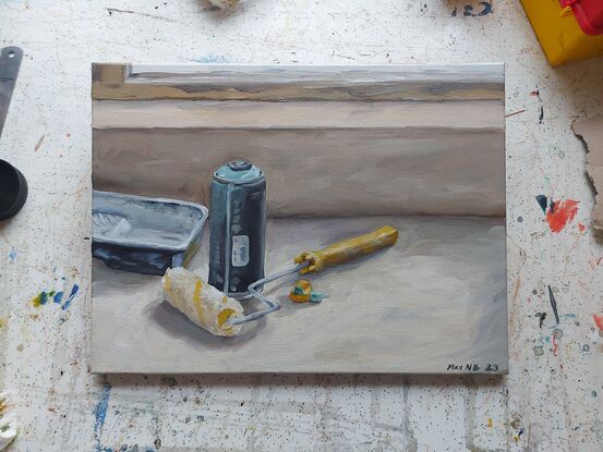 Still life of spray paint can, paint tray, paint roller and spray paint nozzle on table.