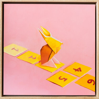 An origami bunny playing hopscotch on cut out square against a pink background