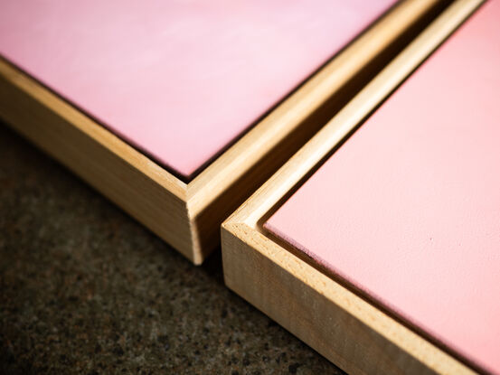 An origami bunny playing hopscotch on cut out square against a pink background