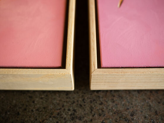 An origami bunny playing hopscotch on cut out square against a pink background