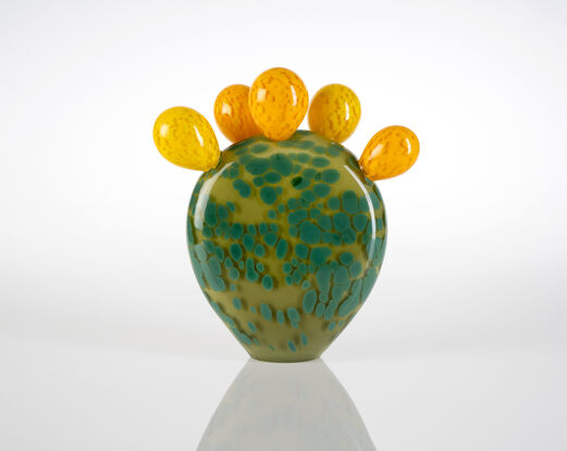 Upright glass sculpture, a large green flat leaf with five rounded yellow buds attached on the top.