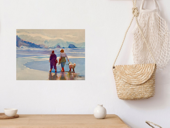 An artwork showing two women walking their dog on the shore at the edge of the ocean.