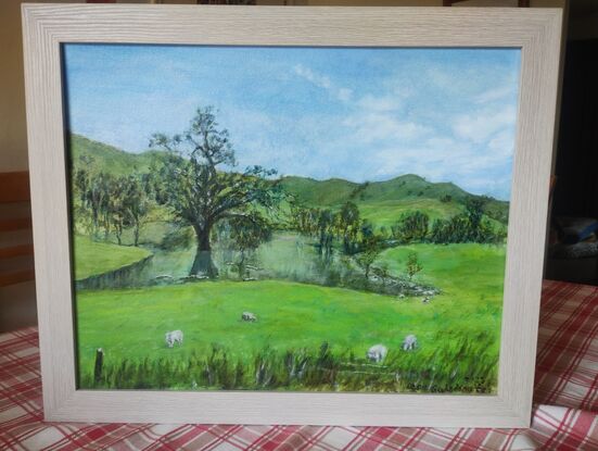 River, flooded trees,  very green pastures and  hills. Blue sky.  Sheeps grazing 