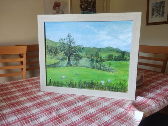 River, flooded trees,  very green pastures and  hills. Blue sky.  Sheeps grazing 