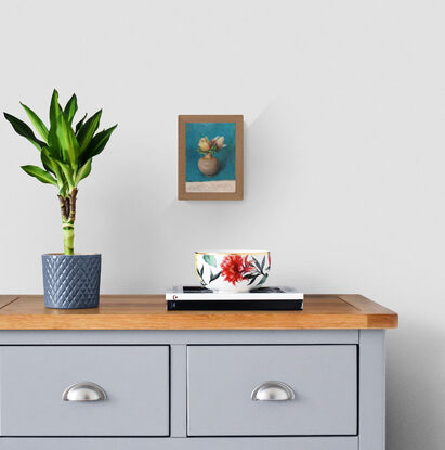 white flower buds in a small vase in a blue background