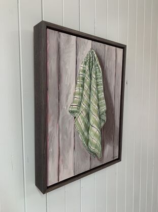 Checkered green tea towel hanging on a grey paneled wall 