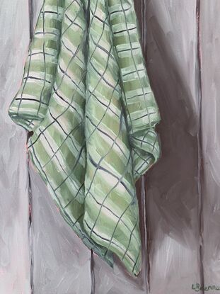 Checkered green tea towel hanging on a grey paneled wall 