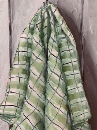 Checkered green tea towel hanging on a grey paneled wall 