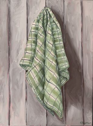 Checkered green tea towel hanging on a grey paneled wall 