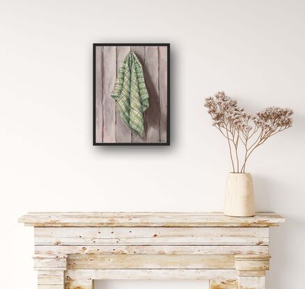 Checkered green tea towel hanging on a grey paneled wall 