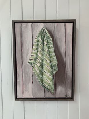 Checkered green tea towel hanging on a grey paneled wall 