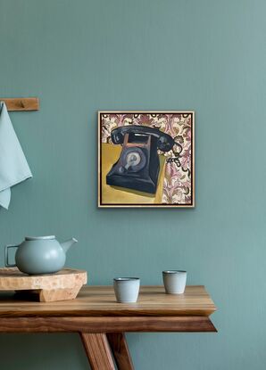 Vintage black windup telephone with blush pink and green leaf pattern wallpaper