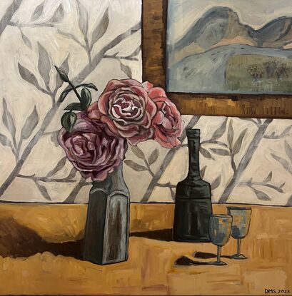 A blue vase with three pink roses sits near a vintage wine bottle and two glasses with a leaf motif wallpaper