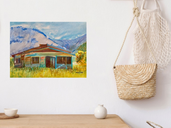  artwork showing a wood cabin in the foothills of the mountains

