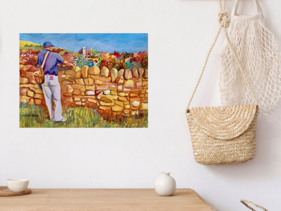 artwork showing a man leaning on a dry stone wall looking at a distant church 
