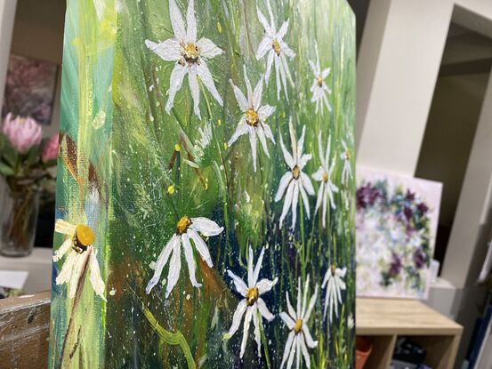 A snapshot of little white flowers dancing in the breeze. There are splashes of yellow, warm ochre and vivid greens in stark contrast to the beauty of the white flowers. 