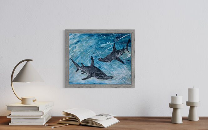 Two hammerhead sharks in shades of grey and black, swimming through an ocean of blues.