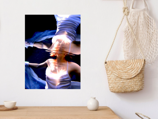 Young woman rising through the surface of the water in a white dress - capturing a mirrored reflection of light.