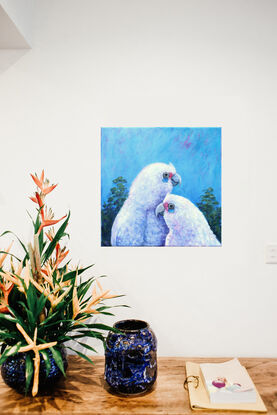 Two white corellas nestling each other against a blue sky background