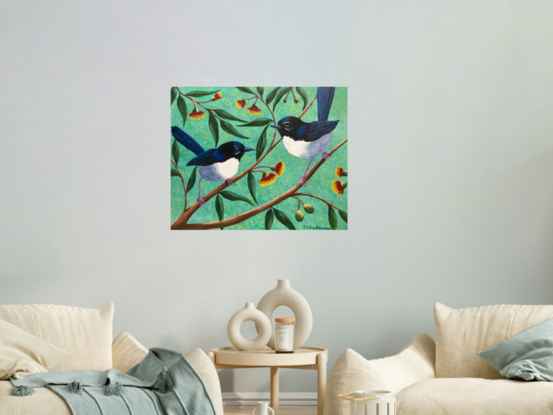 Two Willy Wagtails chattering away on branches with red gum blossoms and gum leaves in the background. Background is a soft pale green.