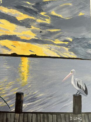 A boy fishing next to the river while a pelican watches.