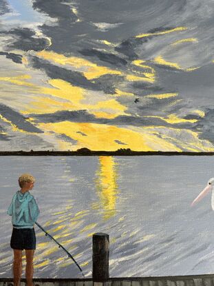 A boy fishing next to the river while a pelican watches.